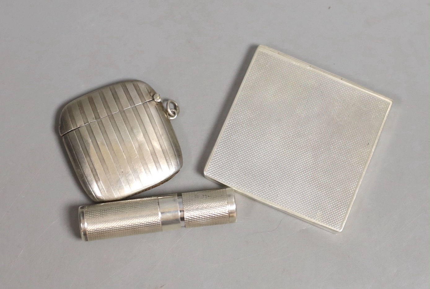 A George VI part engine turned silver cigarette case?, by Asprey & Co, London, 1945, 68mm, an earlier silver vesta case by Asprey & Co Ltd and a modern silver cased atomiser, retailed by Asprey.